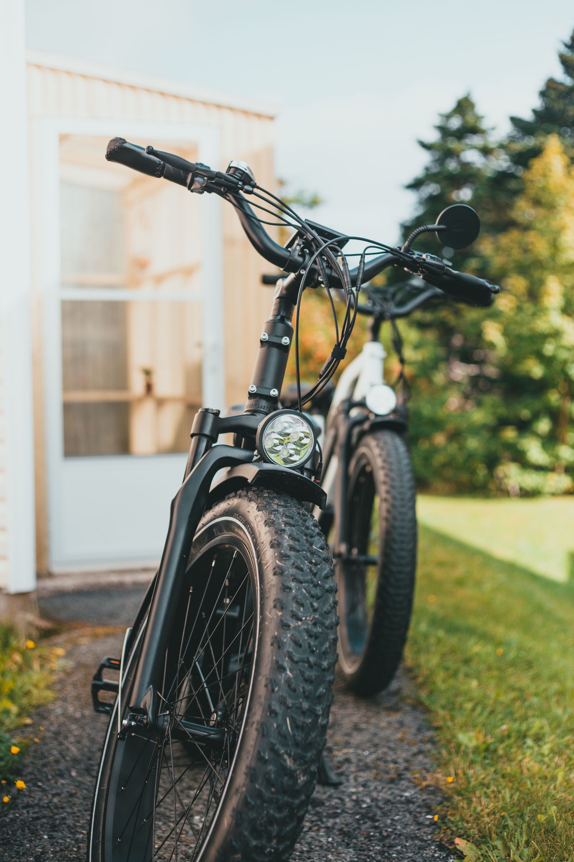 Close-up of black fat tire bicycles parked on a pathway outdoors, highlighting their rugged design.