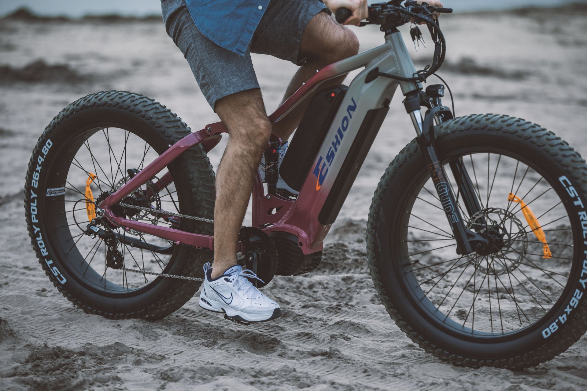 A man enjoys outdoor leisure riding a fat tire electric bike on a sandy beach.
